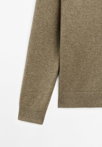 Olivgrön tröja med mjuk textur, ribbad ärmslut och nederkant. Enkla stickade detaljer med rak skärning och minimal dekoration.