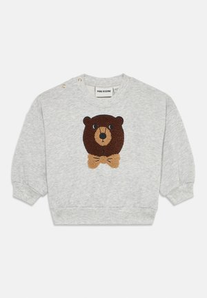 Sweat-shirt gris avec un graphique texturé de visage d'ours brun et un nœud papillon beige. Dispose de boutons-pression sur l'épaule gauche.