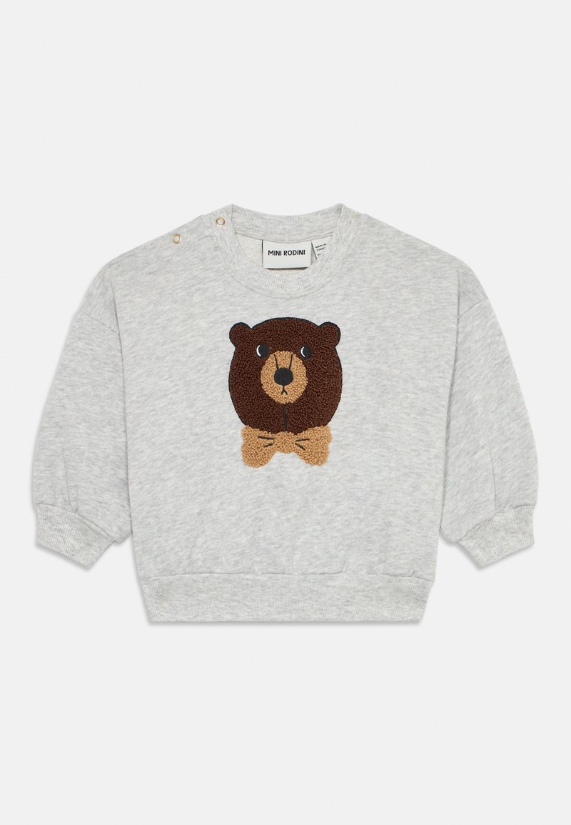 Grå hettegenser med grafikk av et teksturert brunt bjørneansikt og et lysebrunt sløyfebånd. Har trykknapper på venstre skulder.