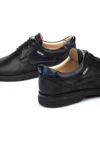 Chaussures en cuir noir avec une finition lisse, bout arrondi et léger rembourrage. Caractéristiques de branding discret et d'un talon texturé pour une adhérence supplémentaire.