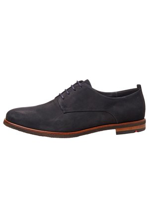 Tummansininen nahkakenkä, jossa on sileä pinta, nauhakiristys ja ohut profiili. Kenkässä on ruskea yksityiskohta pohjassa ja litteät nauhat.