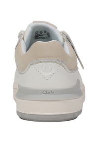 Sneaker bianco con un tallone in suede beige chiaro, suola in gomma e logo Clarks di lato. L'interno presenta una fodera morbida.