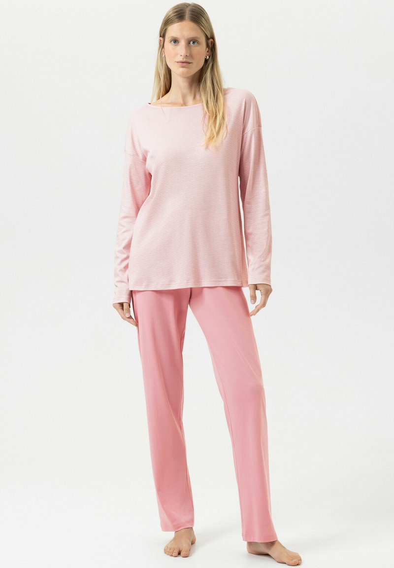 Haut à manches longues rose pâle avec un col rond et une texture douce, associé à un pantalon rose assorti de coupe décontractée.