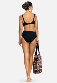 Czarny, prążkowany zestaw bikini z regulowanymi ramiączkami i wysokim stanem, w połączeniu z kolorową torbą w kwiatowy wzór.