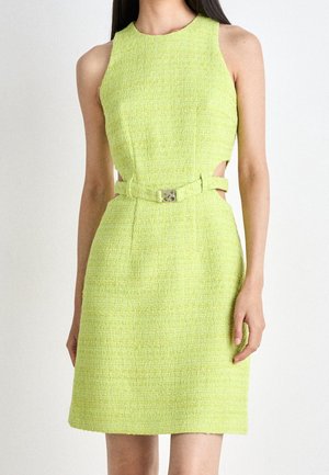 Robe texturée vert citron sans manches avec découpes sur les côtés et ceinture assortie avec boucle métallique, portée par une personne debout.