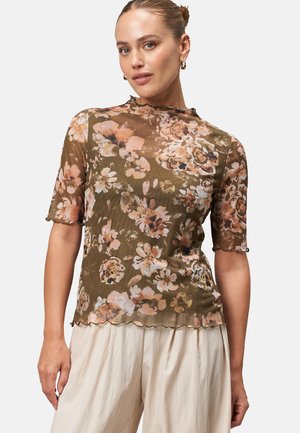 Haut floral en voile vert olive avec de grandes fleurs roses et crème. Les manches courtes et l'ourlet festonné créent une silhouette douce et fluide.