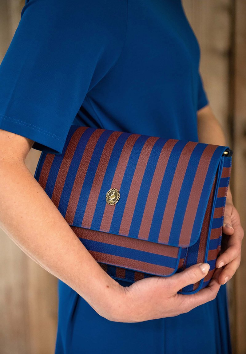 Gestreifte Handtasche aus strukturiertem blauem und braunem Material, verschlossen mit einem goldenen Emblem. Das Design beinhaltet kräftige horizontale Streifen.