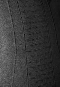 Schwarzer Stoff mit einem strukturierten Muster aus horizontalen Rillen, glatten Bereichen und einem nahtlosen Erscheinungsbild, das ein elegantes Design betont.