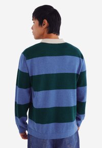 Gestreifter Pullover in grünen und blauen Tönen, mit einem gerippten Kragen, lockerer Passform und weichem Material. Lange Ärmel und Bund sichtbare.