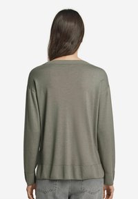 Ljusgrön oversized tröja med rund halsringning, ribbat fåll och sänkta axlar, tillverkad av mjuk, strukturerad tyg.