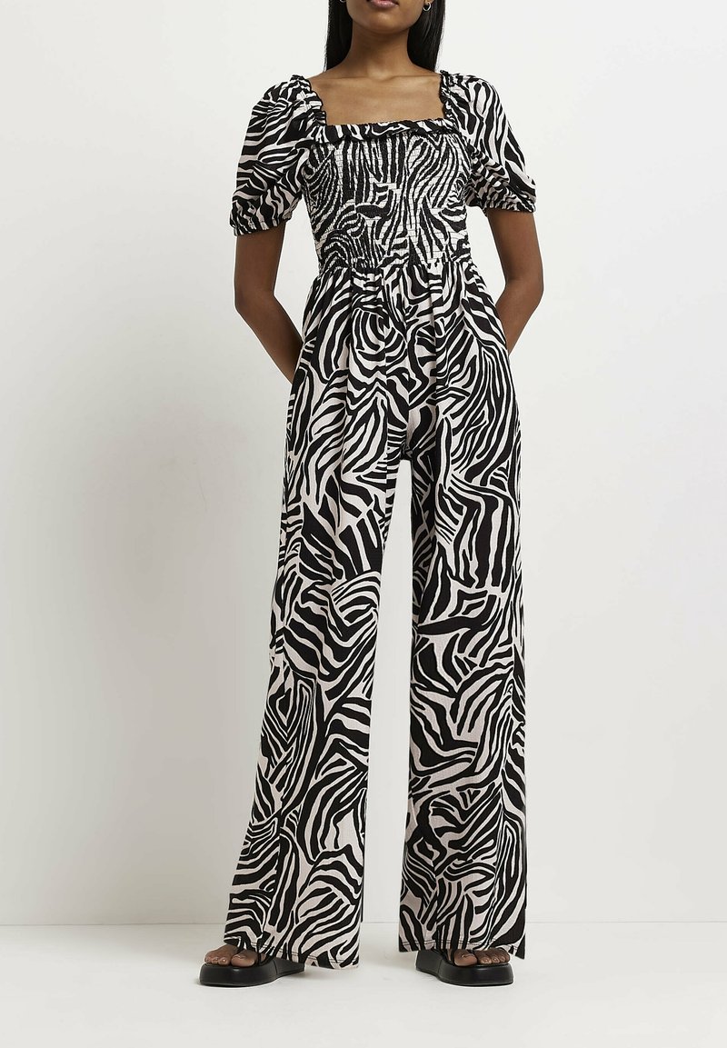 Czarny i biały kombinezon w zebrę z kwadratowym dekoltem, bufkami na rękawach oraz szerokimi nogawkami, wykonany z gładkiego, lekkiego materiału.