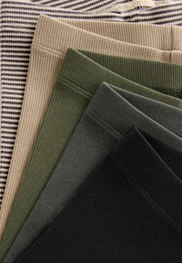 Collants côtelés dans des teintes de vert, beige et noir ; présentent un motif rayé beige. Texture douce avec des ceintures élastiques visibles en haut.