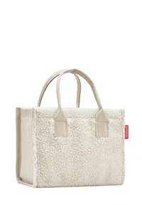 Borsa a tracolla in shearling bianco con dettagli in tessuto beige, due manici corti e un'etichetta rossa sul lato. Forma rettangolare, texture morbida.