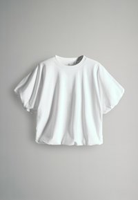 Balta īsām piedurknēm T-kreklā ar apaļu apkakli, brīvā piegriezumā un mīksta kokvilnas tekstūra, ar vienkāršu dizainu un bez redzamas zīmola.