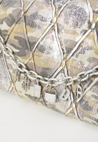 Lædertaske i camouflage mønster med metalliske detaljer. Indeholder sølvfarvet kædetrækt med mærkecharms og struktureret stof.