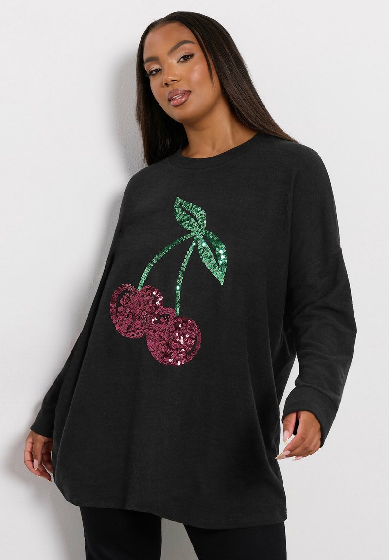Czarna, oversize bluza z wzorem wisienek wykonanym z cekinów; zawiera dwie czerwone wisienki i zielone liście, tworząc teksturowany wygląd.