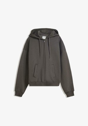 Siva zip-up kapuca s prostorno kapuco, sprednjimi žepi in rebrastimi manšetami. Mehka tkanina, sproščen kroj in minimalističen dizajn.