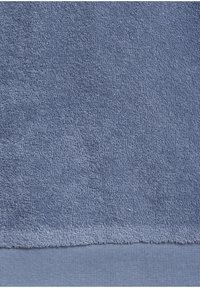 Blue terry towel with a soft, textured surface. Features a smooth, flat woven edge at the bottom, providing a contrasting detail.