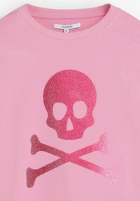 Hanorac roz cu un design strălucitor de craniu și oase încrucișate în nuanțe de roz închis pe partea din față, având o decolteu rotund și etichetă de marcă vizibilă.