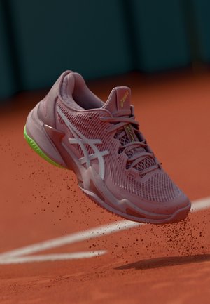 Roosa tennissuss, millel on tekstureeritud võrgust ülemine osa, valged aktsendid ja rohelise tallaga. Omab ümarat varvast ja mitut lacingi silmust.