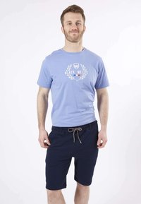 T-shirt en coton bleu clair avec un imprimé graphique en blanc et rouge ; assorti à un short bleu marine avec cordon de serrage et poches latérales.