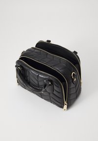 Černá prošívaná kožená kabelka se zlatými zipy, dvojitými uchy a třemi přihrádky. Obsahuje texturovaný vzor a dekorační akcenty.