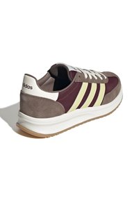 Bruna och vinröda sneakers med tre gula ränder, vita detaljer, i mocka och textilmaterial, som har en vadderad krage och gummisula.