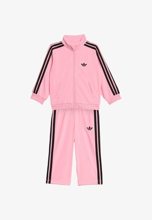 Kinder-Trainingsanzug von Adidas in Pink mit schwarzen drei Streifen an Ärmeln und Hosen, Reißverschlussjacke sowie Adidas-Trefoil-Logos auf Brust und Bein.