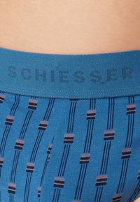 Blauwe boxershorts met een patroon en een zachte elastische tailleband. Het ontwerp heeft verticale strepen en kleine rechthoekige accenten in contrasterende kleuren.