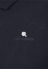 Námořnická modrá bavlněná polo tričko s žebrovaným límcem, bílé vyšitým logem a grafikou postavy v brýlích na hrudi.