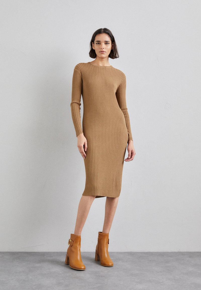 Robe marron à manches longues et nervures, avec une silhouette ajustée et un col rond, accompagnée de bottes à talons beige à la cheville avec un détail de boucle.