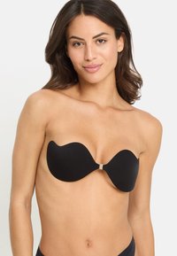 Black strapless adhesive bra with a smooth texture, contoured shape, and gold hardware in the center, designed for a seamless fit.