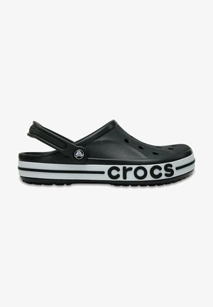 Zwarte Crocs klompen met een achterkantriem, voorzien van ventilatiegaten, een witte gestreepte zool en het "crocs" logo aan de zijkant.