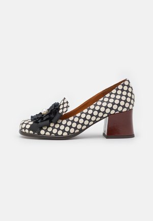 Chaussure à talon moyen à pois noirs et blancs avec bout carré, ornée d'une fleur en tissu noir et d'un détail en perle à l'avant.