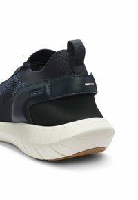 Dunkelblauer Mesh-Sneaker mit schwarzen Akzenten, strukturiertem hinterem Bereich und weißer Sohle. Verfügt über Markenzeichen und ein gemustertes Design am Obermaterial.