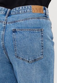 Lichtblauwe denim jeans met een hoge taille, voorzien van een lederen label met de tekst "VMD" en een enkele achterzak met zichtbare stiksels.