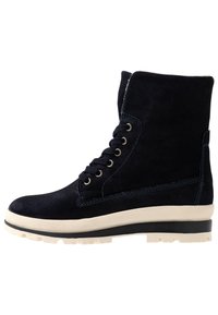 Botas de ante azul marino hasta el tobillo con puntera redonda, superficie texturizada, seis ojetes de metal y una suela de goma blanca con un patrón de tracción resistente.