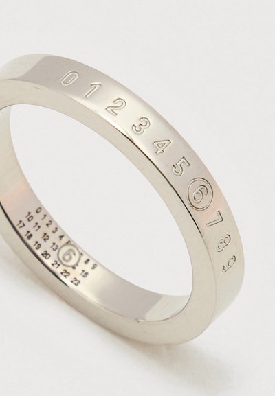 Ασημένιο δαχτυλίδι με χαραγμένους αριθμούς 0-9 στην εξωτερική πλευρά και σημάδια μεγέθους στην εσωτερική πλευρά; ομαλή, γυαλισμένη επιφάνεια, στρογγυλό σχήμα.