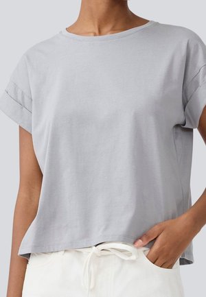 Jasnoszary t-shirt z krótkim rękawem wykonany z miękkiej bawełny, o luźnym kroju, z okrągłym dekoltem i podwiniętymi rękawami.