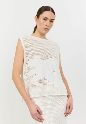 Top smanicato bianco lavorato a maglia con un motivo floreale, caratterizzato da una vestibilità ampia e un design in rete testurizzata. Abbinato a un pantalone simile per texture.