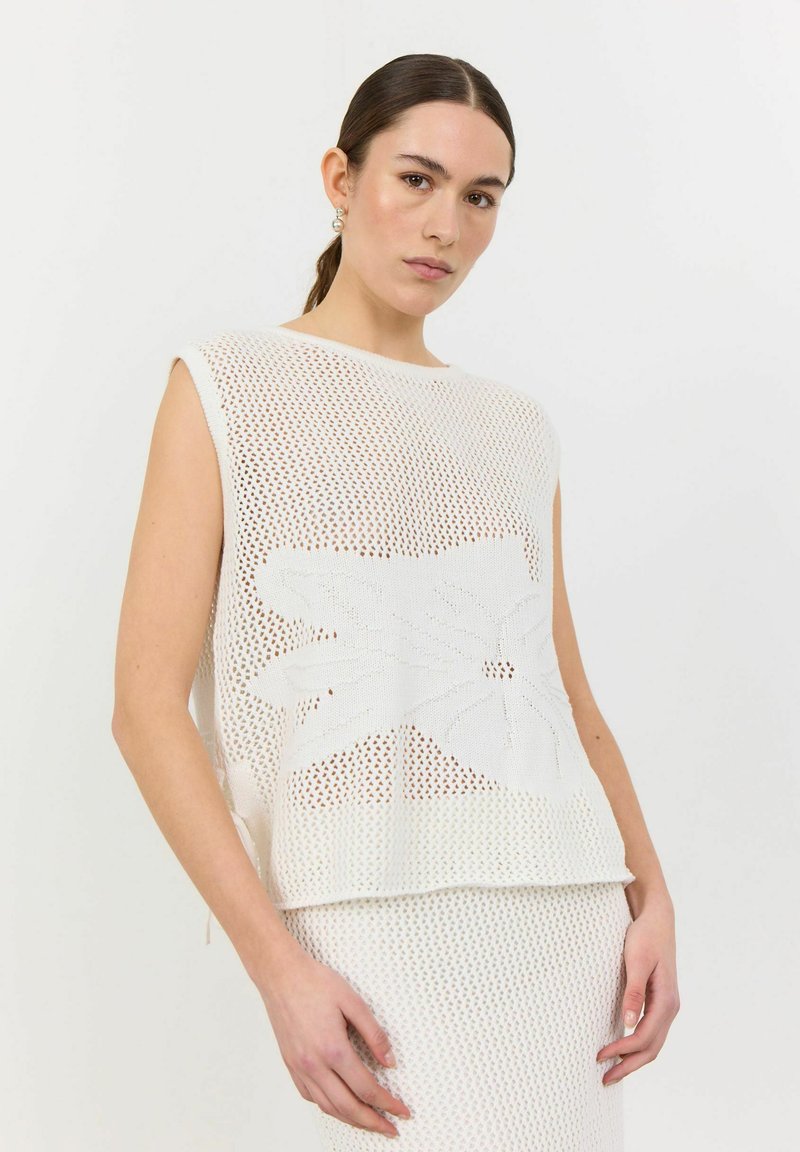 Vit stickad ärmlös topp med blommönster, med en lös passform och texturerad nät-design. Kombineras med en underdel i liknande textur.