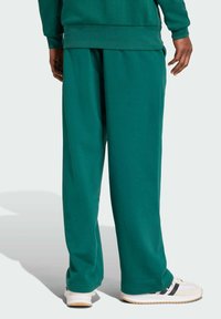 Gröna mjukisbyxor av mjukt tyg, med en avslappnad passform, elastisk midja och sidofickor. Matchas med vita sneakers.