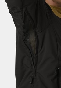 Schwarze Jacke mit einem mesh-gefütterten Belüftungsbereich unter dem Arm, mit glatter Textur und dezenten Nähten. Reißverschluss auf der Seite.