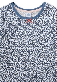 Baumwolloberteil mit blauem Hintergrund und kleinem weißen Blumenmuster. Rundhalsausschnitt mit kontrastierendem blauem Rand und roter Schleifenverzierung.