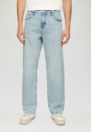 Lichtblauwe, loszittende denim jeans met rechte pijpen, vijf zakken en subtiele vervaging. Gestyled met witte sneakers.