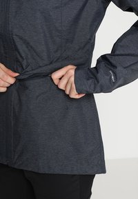 Ciemnoszara kurtka z teksturowanym wzorem, z zamkiem błyskawicznym i ściągaczem w talii. Mankiety oznaczone etykietą "DRYVENT".