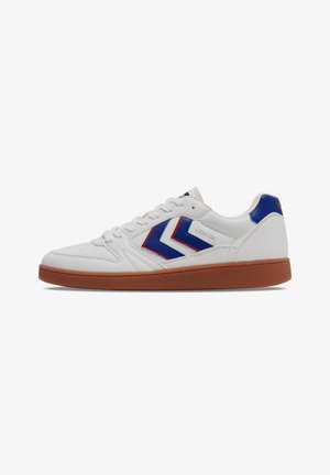 White leather sneaker with blue and red chevron accents, brown rubber sole, and round toe. Features lacing and heel tab detail.