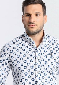 Weißes Hemd mit Button-Down-Kragen und marineblauen Floralmustern, einem kleinen gestickten Logo auf der Brust und einem klassischen Kragen.