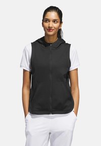 Black sleeveless hooded vest with a front zipper and two pockets, worn over a white short-sleeve shirt. Smooth fabric texture.