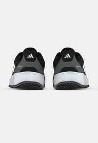 Čierne a sivé športové topánky s hornou časťou z oka, bielou medzipodrážkou a textúrovanou gumovou podrážkou. Tri biele pruhy zdobia boky.